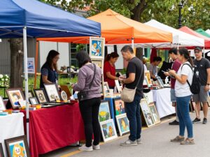 Artists and vendors at the Birmingham Summer Market showcasing local creations and engaging with customers.
